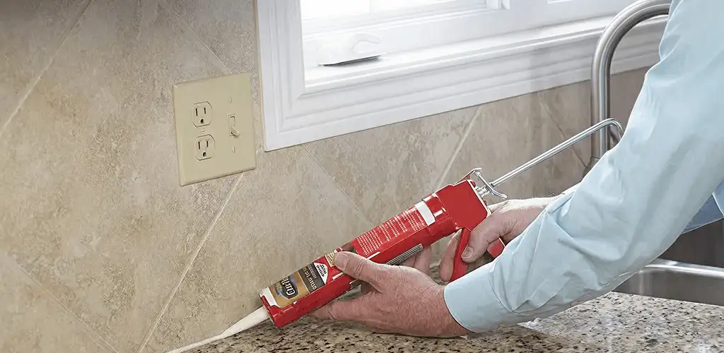 Handyman applying caulk along a kitchen backsplash and countertop seam in Tampa, FL