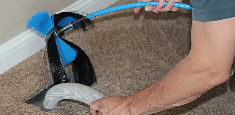 Dryer vent cleaning technician brushing lint from a vent line in Tampa, FL