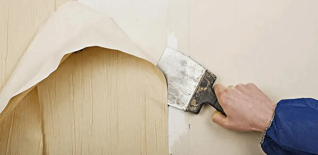 Handyman removing wallpaper with a scraper for wall preparation in Tampa, FL