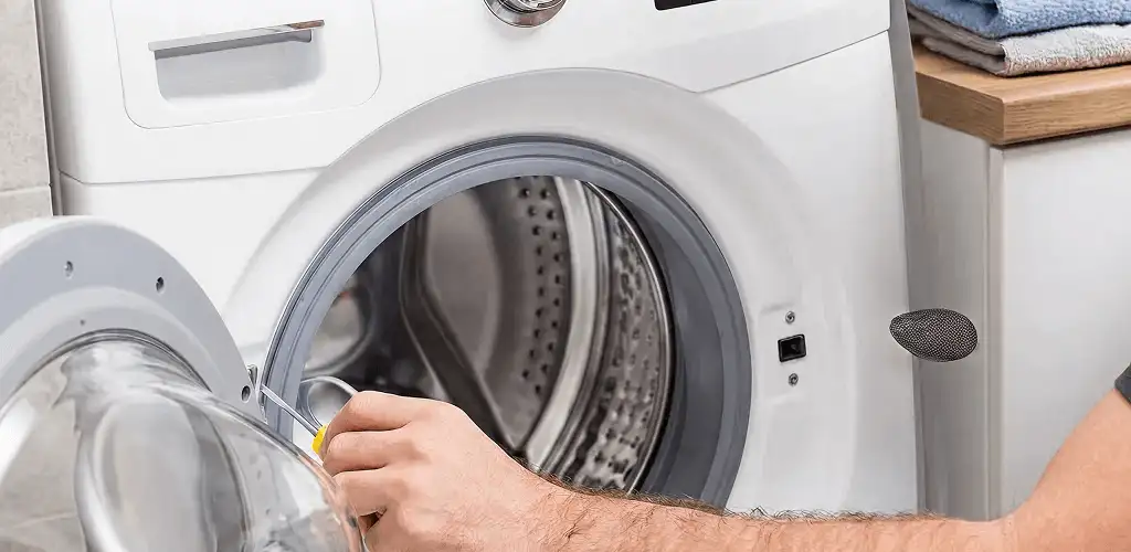 Handyman repairing a front-load washing machine and inspecting the drum in Tampa, FL