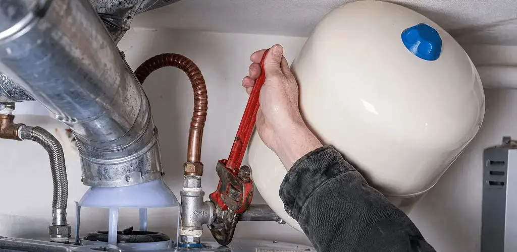 Water heater repair technician tightening plumbing connections near a tank unit in Tampa, FL